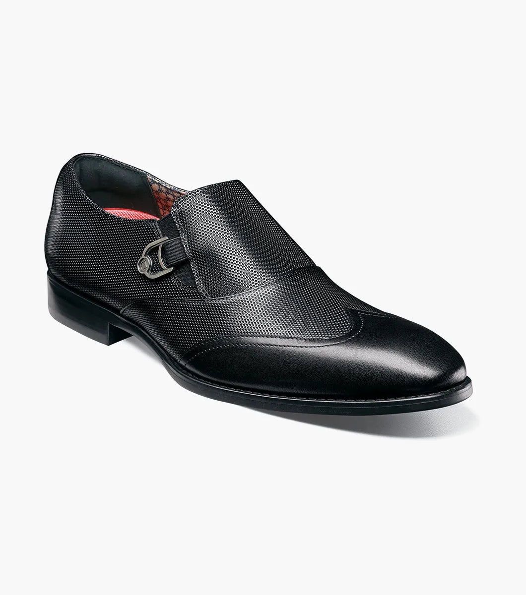 The STACY ADAMS Lockwood Wingtip Ornament Slip On in black (25767-001) features a textured upper, wingtip design, and is displayed on a white background.