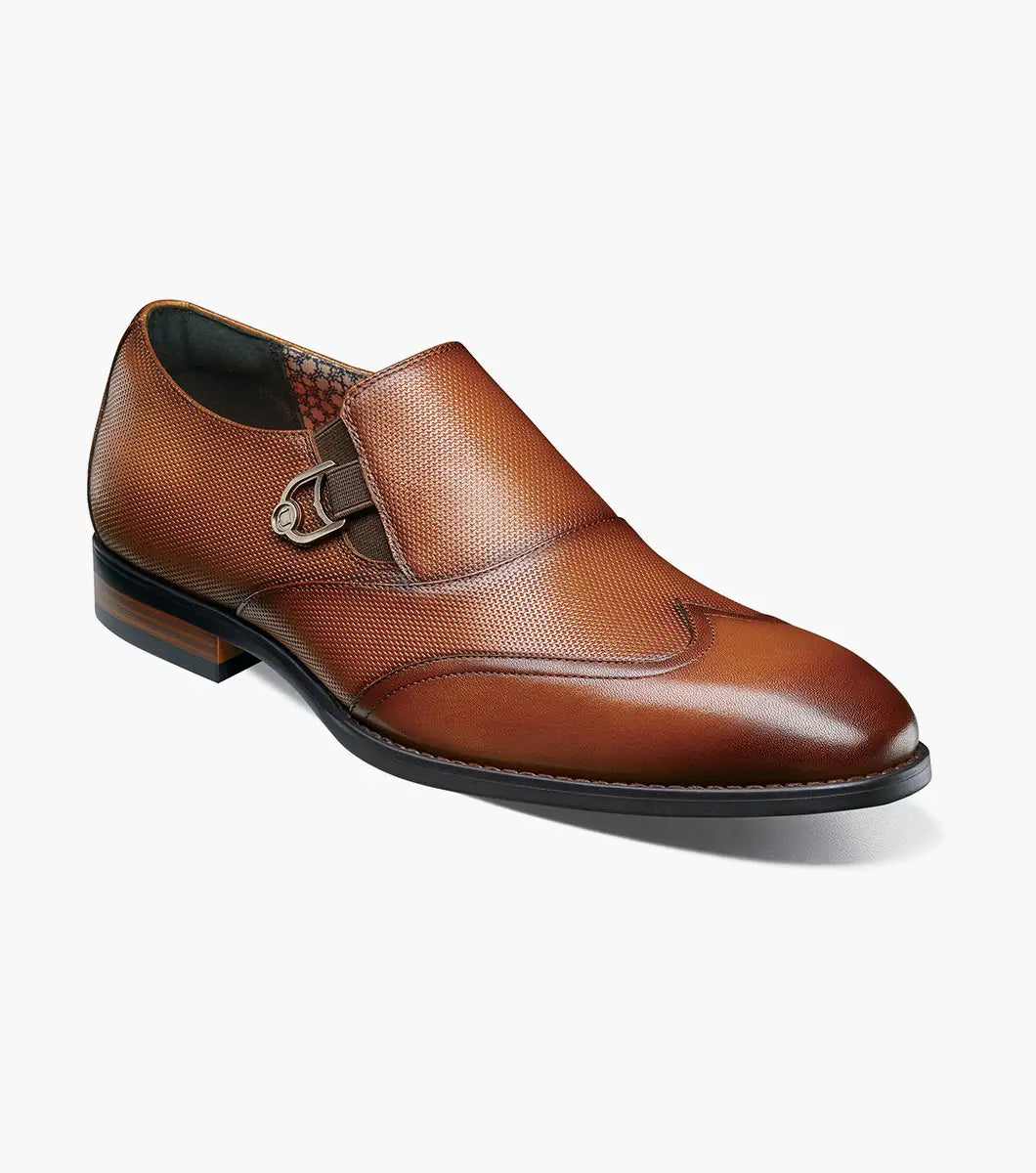 The Stacy Adams Lockwood Wingtip Ornament Slip On in Cognac features classic leather style with a textured upper, single side buckle, and low stacked heel—perfect for men seeking timeless dress shoes.
