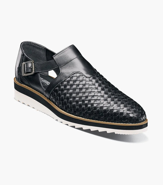 The Stacy Adams Alvarado Woven City Sandal features a black woven leather upper, buckle strap, closed toe, memory foam insole, and a white ridged sole with tan accent.