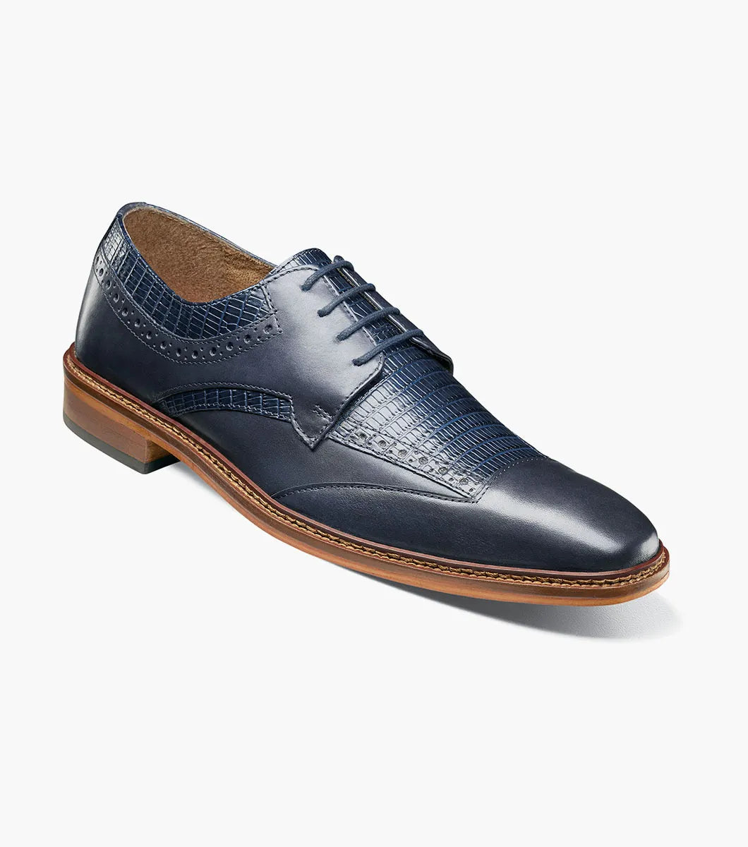The STACY ADAMS Gambetta Modified Cap Toe Oxford (Navy, 25780-410) is a navy blue leather dress shoe featuring a textured pattern, brown sole, RedZone footbed, and lace-up closure, displayed on a white background.