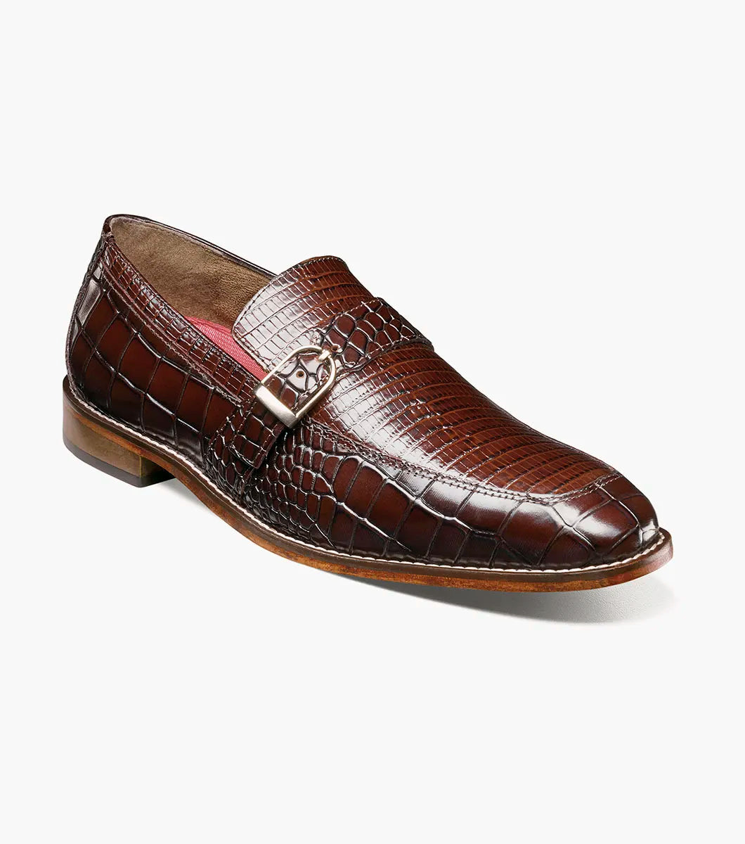The Stacy Adams Rubiano Moc Toe Buckle Strap Slip On in brown (style 25787-200) by STACY ADAMS is a single leather loafer featuring a crocodile print, slip-on design, side buckle detail, and low heel, displayed on a white background.