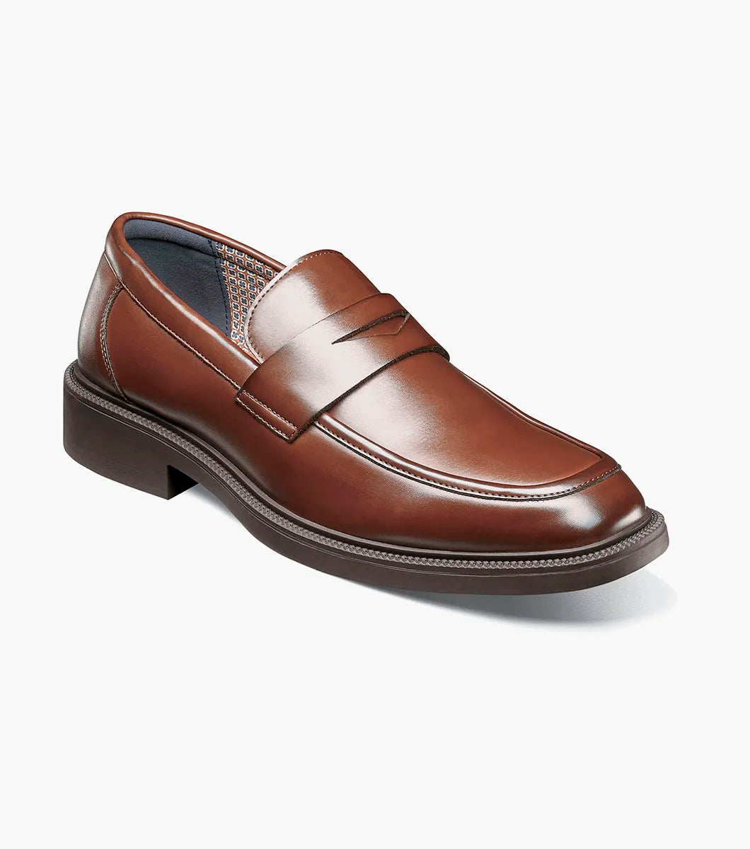The STACY ADAMS Everett Moc Toe Penny Slip On in brown (style 25790-200) features a classic moc toe design with stitching details, a low heel, a rounded toe, and cushioned comfort from its memory foam insole, shown here against a plain white background.