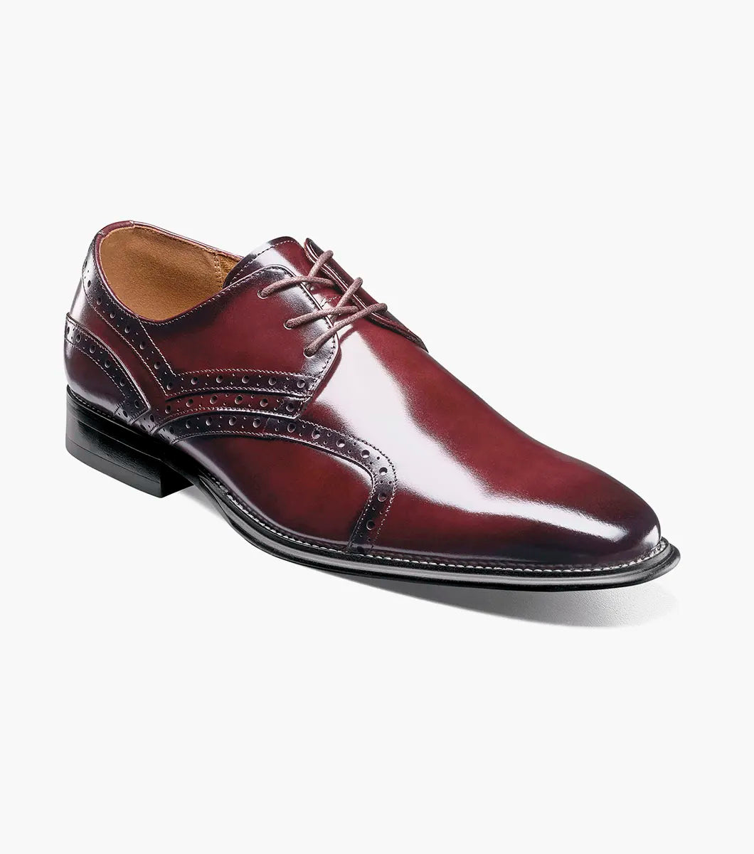 The Stacy Adams Alexander Plain Toe Oxford in Burgundy (style 25791-601) is a men’s dress shoe crafted from glossy oxblood calf leather, featuring brogue detailing, a lace-up closure, and a low black heel, displayed against a plain white background.