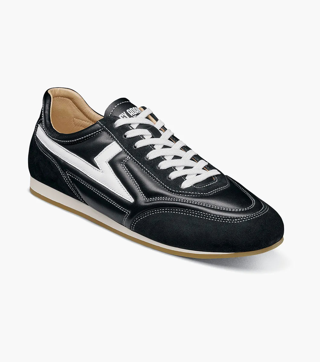 The Stacy Adams - Action 150 Sporty Lace Up sneaker (style 25797-001) is a black, low-top shoe featuring white laces, sporty lace-up design, distinctive white side detailing, and a brown rubber sole. It is shown in a side profile view on a plain white background.