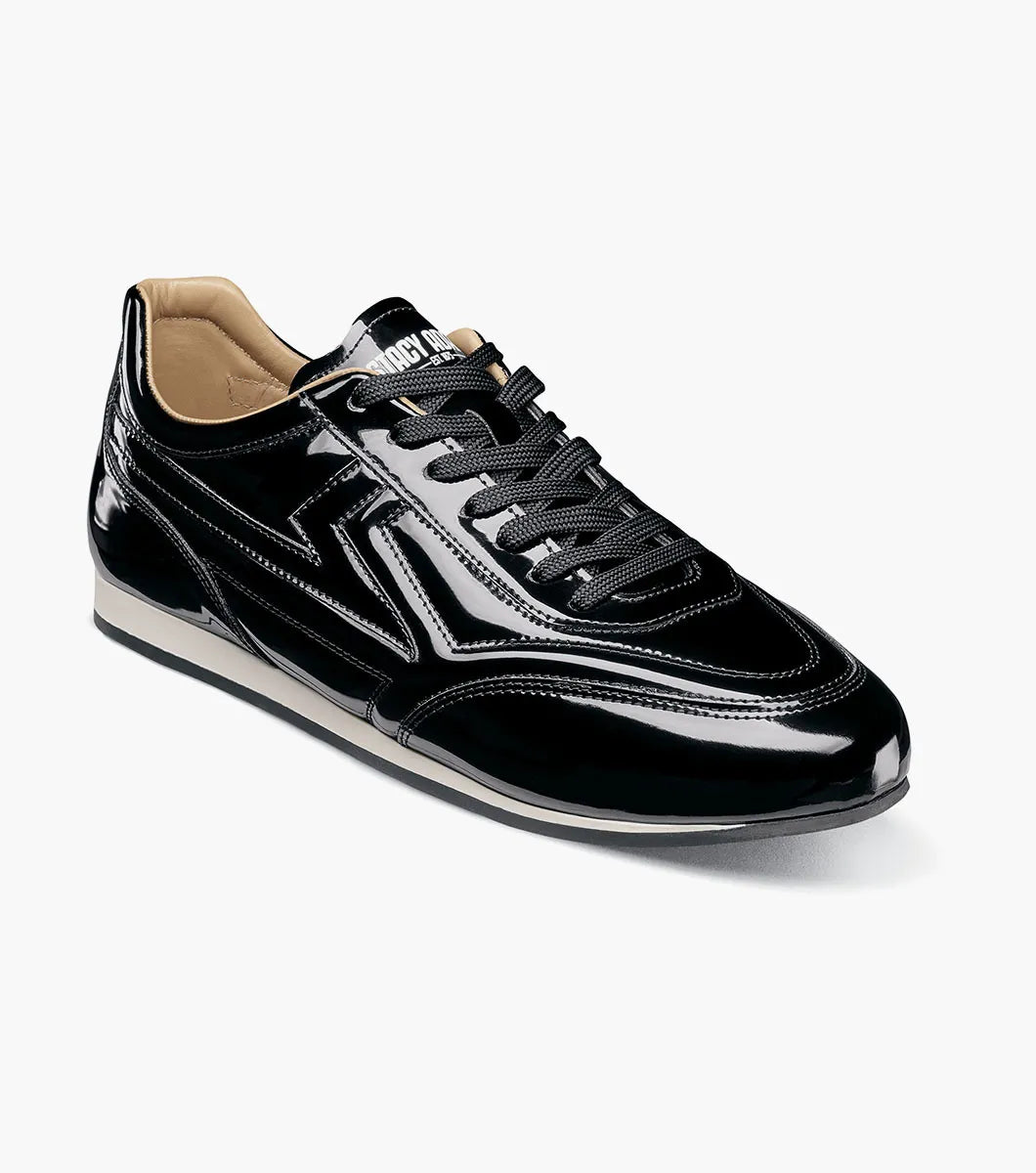 The STACY ADAMS Action 150 Sporty Lace Up in Black Patent (25797-004) features black laces, a white sole, and decorative stitching—presented on a white background for a sleek modern update to men’s casual footwear with a sporty lace-up design.