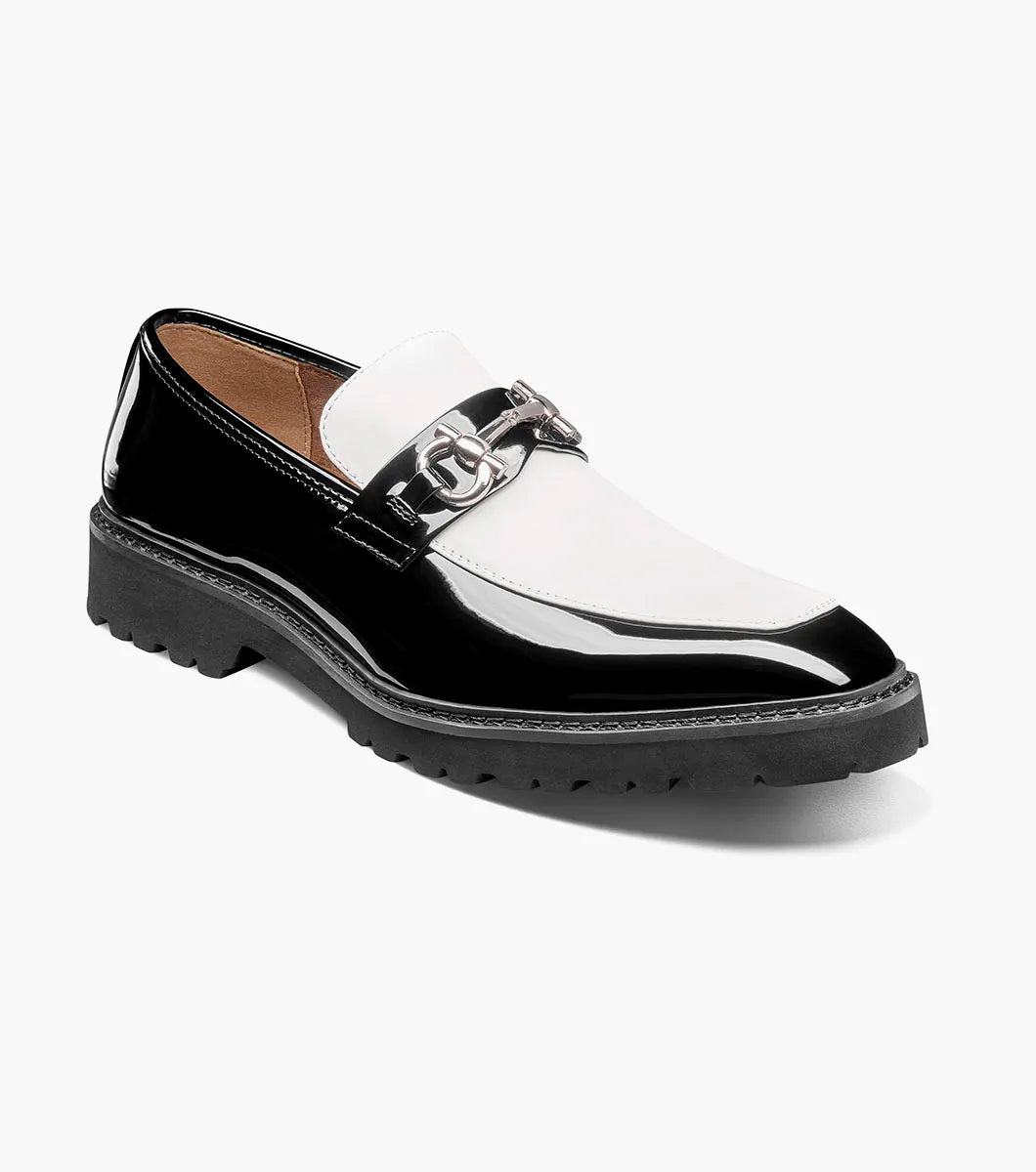 The Stacy Adams Carabello Moc Toe Bit Slip On in Black with White (25804-111) by STACY ADAMS is a black and white loafer featuring a chunky sole, metallic chain detail on the upper, and a comfortable memory foam insole, displayed on a white background.