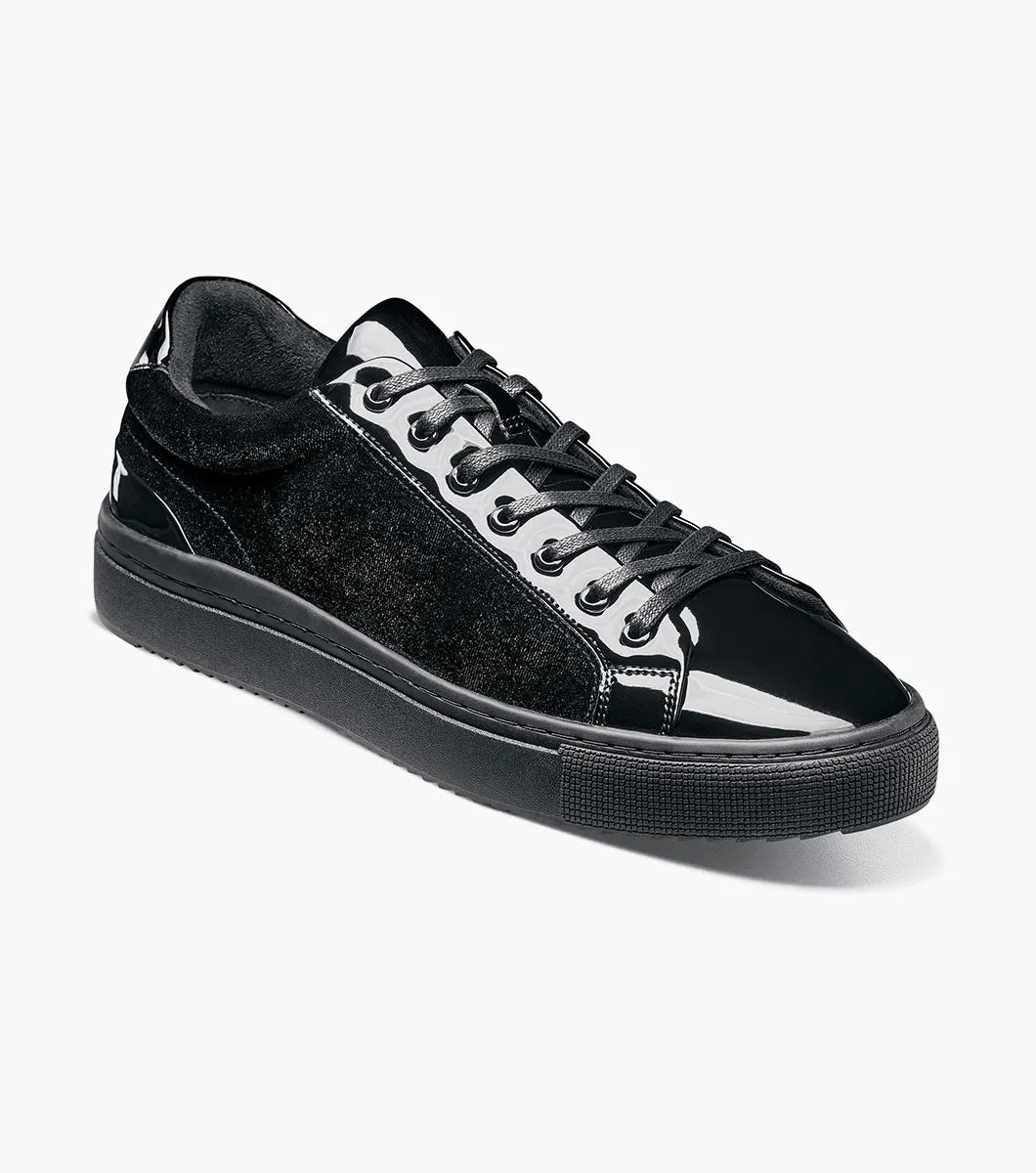 The Stacy Adams Dante Lace To Toe Sneaker in Black Smooth (Style 25806-005) features glossy patent leather and suede paneling, black laces, and a black rubber sole. Displayed on a white background, this STACY ADAMS low-top sneaker offers a sleek lace-to-toe design.