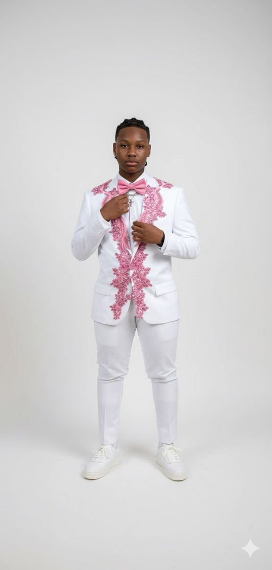 A person wears the Unique Design Menswear custom prom suit—white with pink rhinestones—paired with a matching bow tie and white shoes, standing against a plain white background while adjusting their jacket.