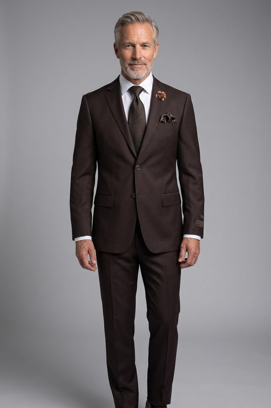 The Tiglio Luxe Novello Brown Pure Wool Men’s Suit TIG1003 features a dark brown European-style single-button jacket, matching trousers, white shirt, patterned tie, pocket square, and lapel pin—modern menswear displayed on a headless mannequin.
