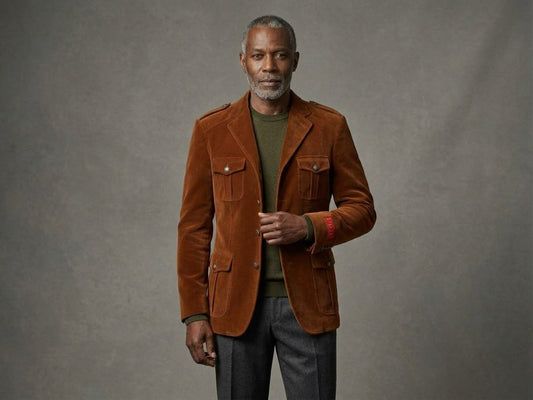 A man wears an Inserch Velvet Military Blazer BL569 Cognac (Size Small) with four front pockets, shoulder epaulets, and military shank buttons over an olive green sweater.