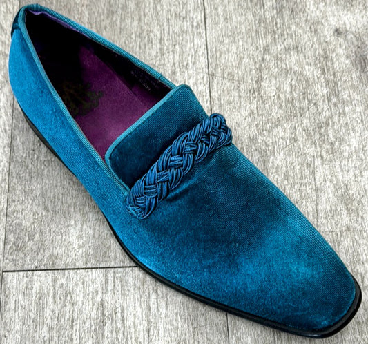 The Exclusive Formal Dress Shoe Teal Solid 6845 by UNIQUE DESIGN MENSWEAR, crafted in Italy, combines elegance and quality with its teal velvet finish and braided upper detail. Presented on a light gray wooden floor, this shoe exudes sophistication.