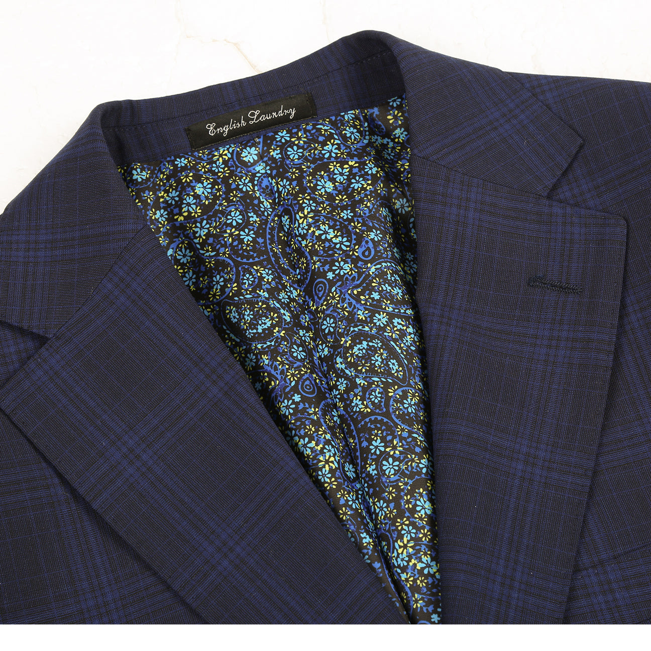 The ENGLISH LAUNDRY Dark Blue Wool Suit EL92-58-555 by English Laundry is a slim fit, plaid wool blazer with two buttons, notch lapels, flap pockets, and a patterned inner lining, shown against a white background.