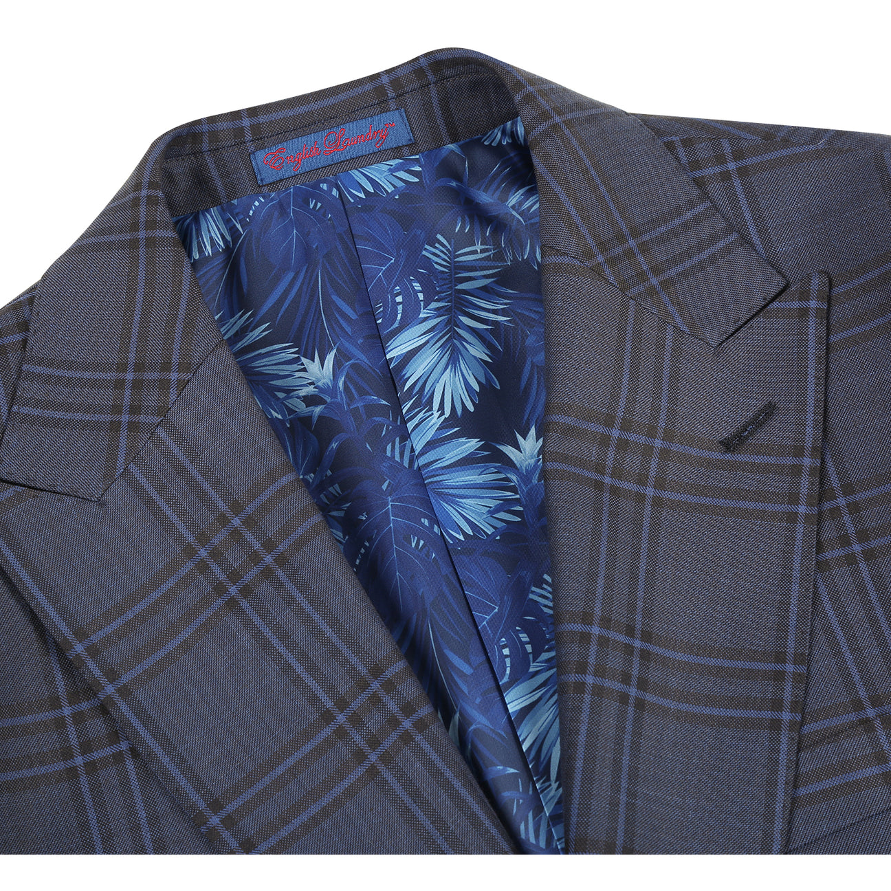 The ENGLISH LAUNDRY Grey Check Suit 12-53-093EL by English Laundry is a men's slim fit grey plaid blazer with two buttons, notched lapels, flap pockets, and a blue tropical-patterned inner lining.