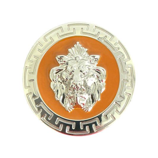 A Matiste round metallic pin with a silver lion head inspired by the Matiste Cognac/Silver Belt Buckle 40mm B40, set on an orange background and bordered by a Greek key pattern.