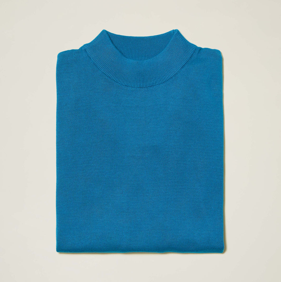 The Inserch Cotton Blend Mock Neck Sweater in True Blue (4308-00101) by Inserch, a soft long-sleeve cotton-acrylic sweater, is neatly folded on a plain off-white background.
