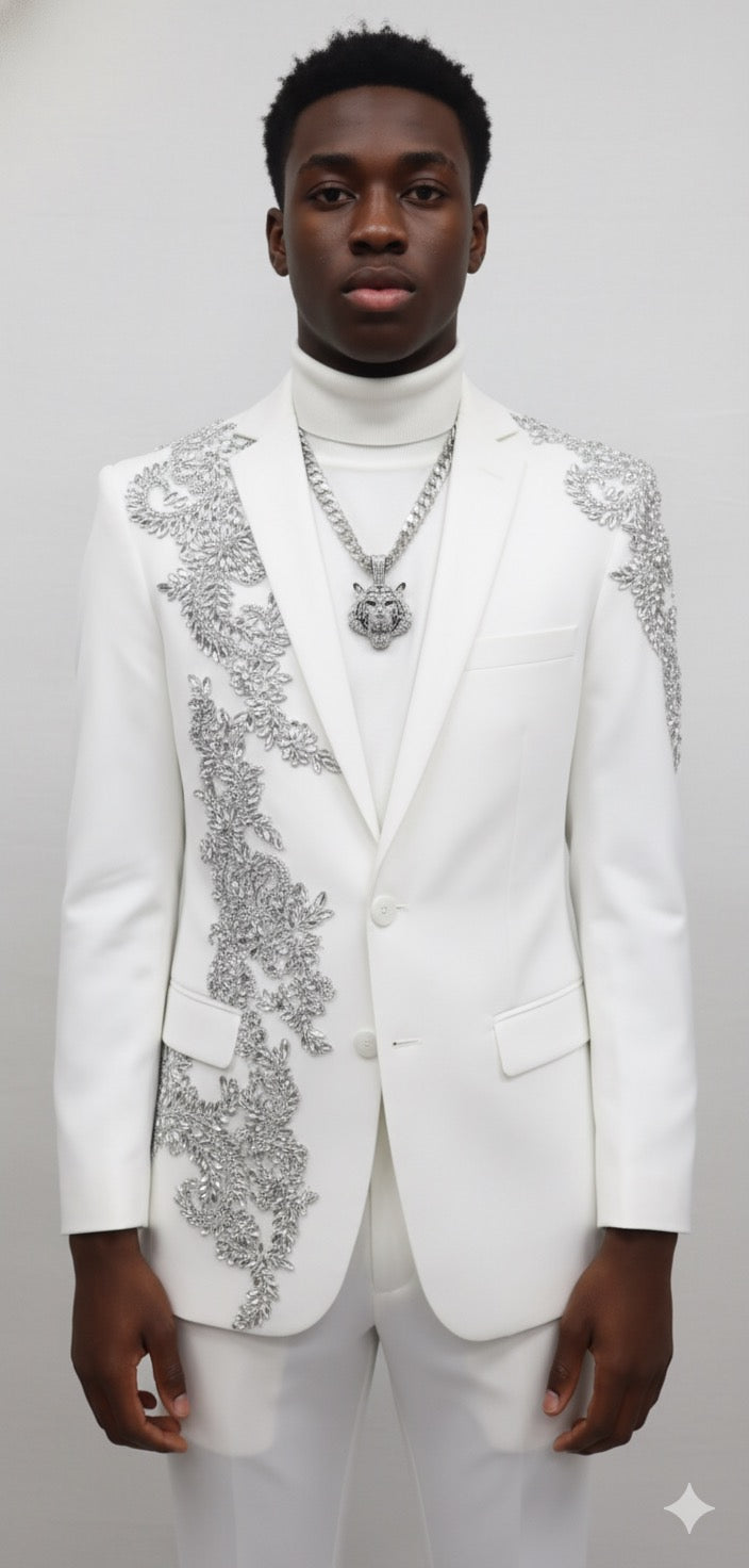 A young man stands against a plain background, wearing the Unique Design Menswear Custom Prom Suit White with Silver Rhinestones, paired with a white turtleneck and a silver chain necklace.