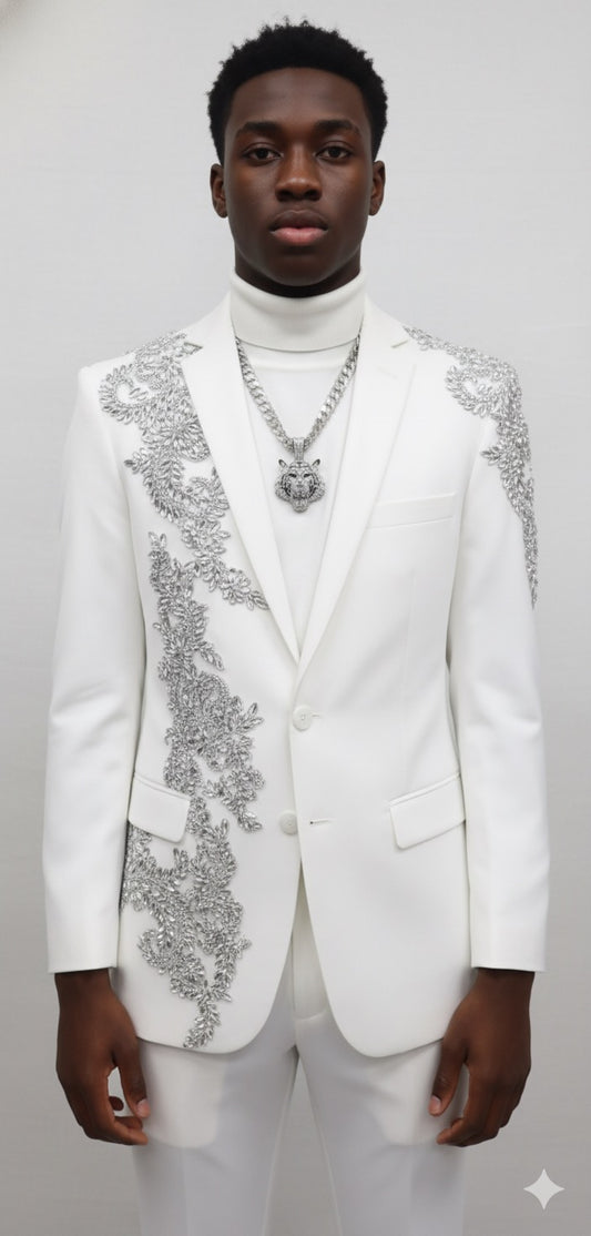 A young man stands against a plain background, wearing the Unique Design Menswear Custom Prom Suit White with Silver Rhinestones, paired with a white turtleneck and a silver chain necklace.