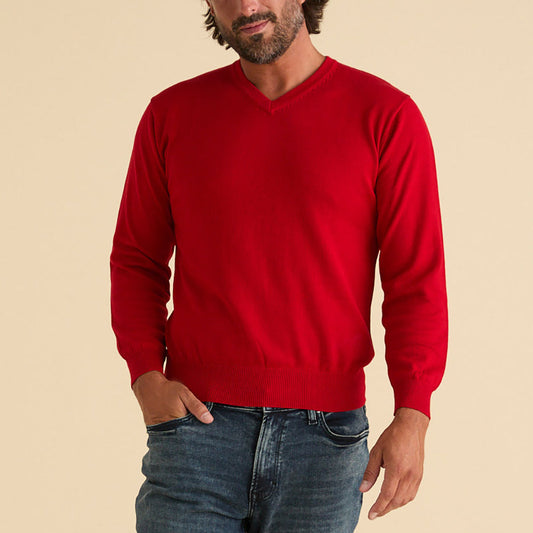 A man in an Inserch Cotton Blend V-Neck Sweater 4608-00030 Red and blue jeans stands with one hand in his pocket against a beige background.