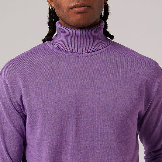 Inserch's cotton blend turtleneck sweaters, part of the 4708 collection featuring ten color options, are elegantly displayed. The vibrant orange, white, and green variations rest on a wooden chair with a patterned cushion, while other regular fit options in red, blue, and black are arranged gracefully on the ground below.