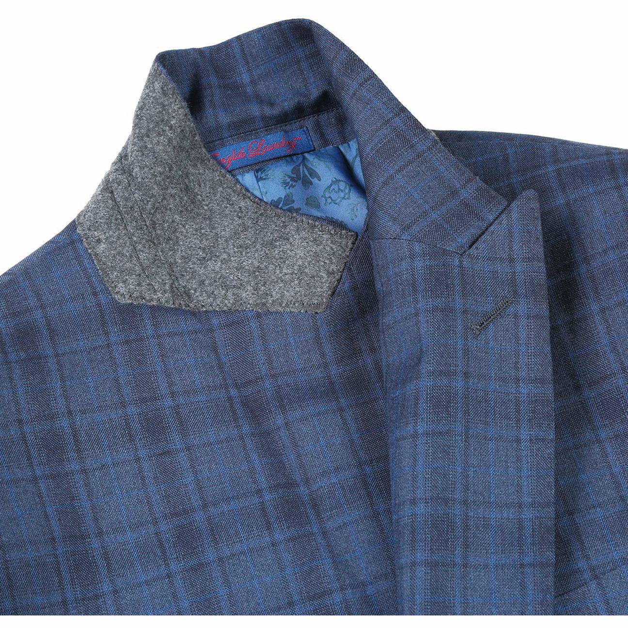 The mannequin is adorned with the ENGLISH LAUNDRY Cadet Blue Check Suit 92-53-095EL, a stylish offering from English Laundry, complemented by an immaculate white shirt and a striped tie. Its elegant peak lapels bring an air of sophistication to the ensemble.