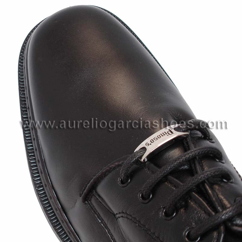 The P-5054 Belka Black Lace up by Pinoso's, part of the Men’s Shoes collection and made in Spain, is a black Nappa leather dress shoe with laces and a metal tag near the eyelets, displayed on a white background.