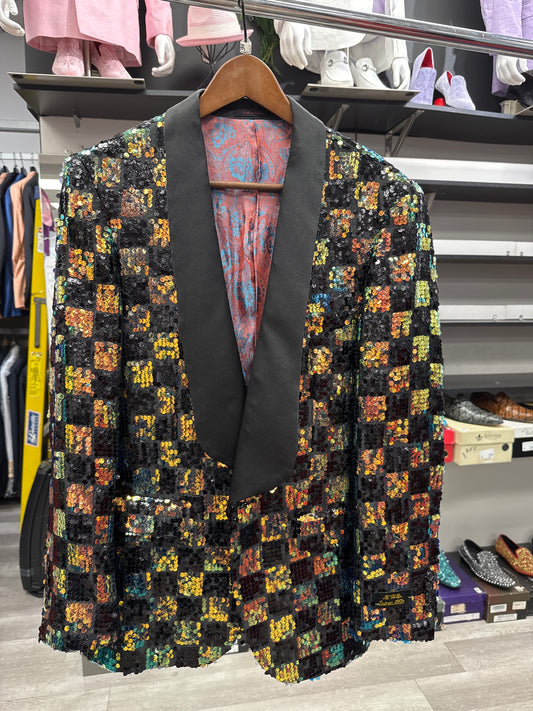 The EJ SAMUEL JACKET 2 CLEARANCE—a sequined blazer featuring a black shawl collar—hangs on a wooden hanger in a clothing store, surrounded by shirts, shoes, and other accessories. Please note: this item is final sale—no returns or exchanges allowed.