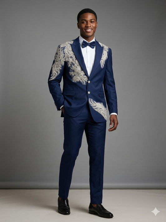 A man models the Unique Design Menswear Custom prom suit, blue silver, featuring a personalized blue jacket with silver embroidery, white shirt, blue bow tie, and black shoes against a plain gray background.