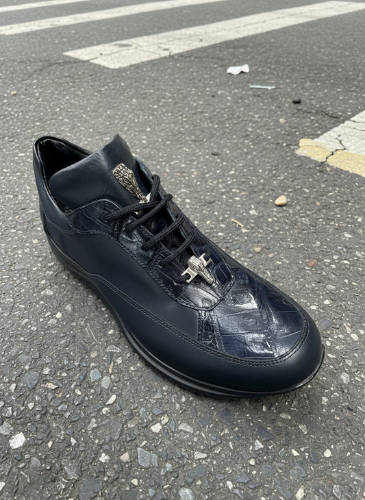 A single Mauri 8900 Navy sneaker (size 8.5 only), featuring textured accents and a metallic lace accessory, is placed on an asphalt road near a crosswalk.