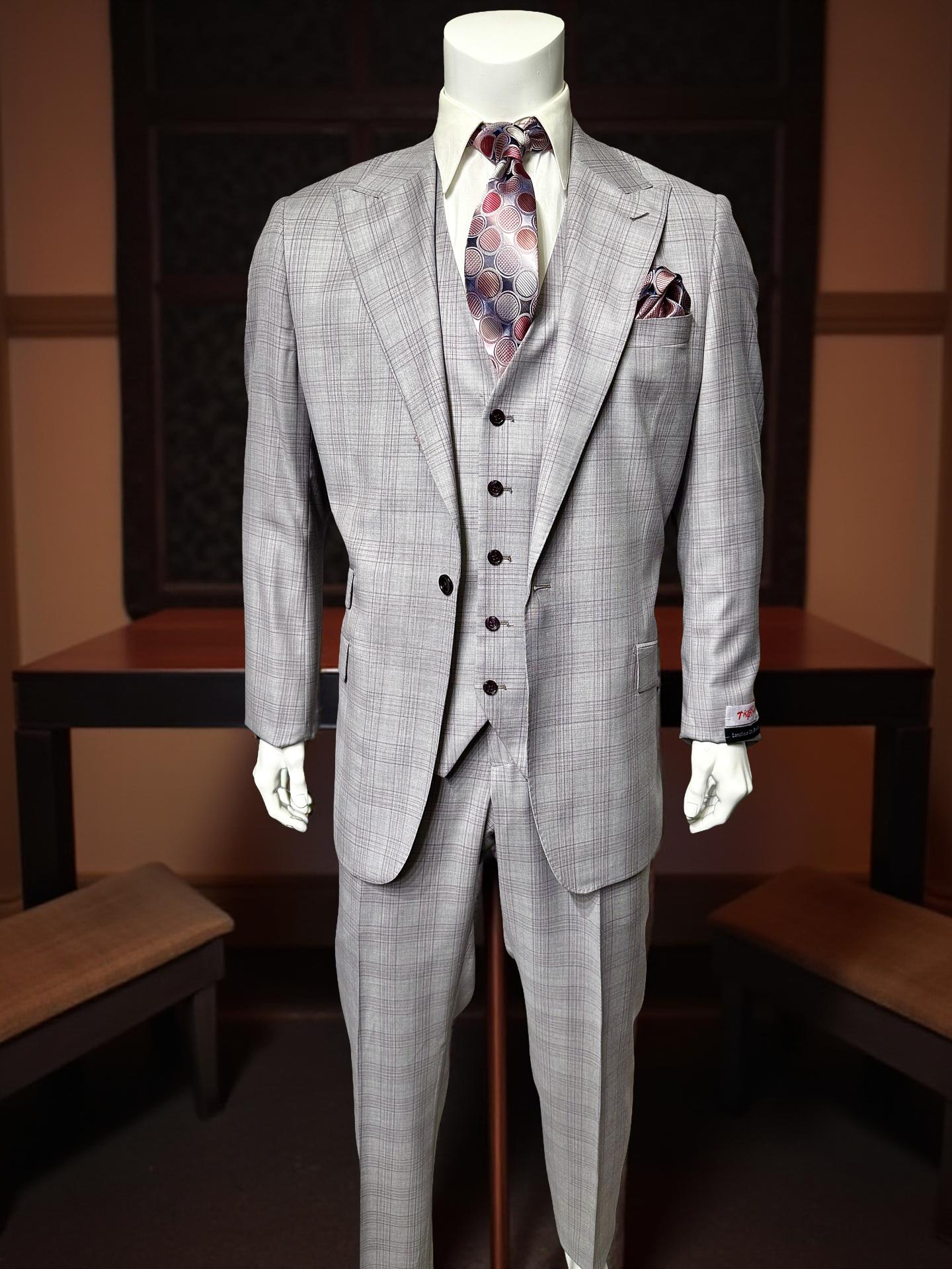 A mannequin indoors by wooden benches and a dark table wears a Tiglio Rosso Portofino Semi Wide Leg TL8059 suit, styled with a patterned tie and pocket square.