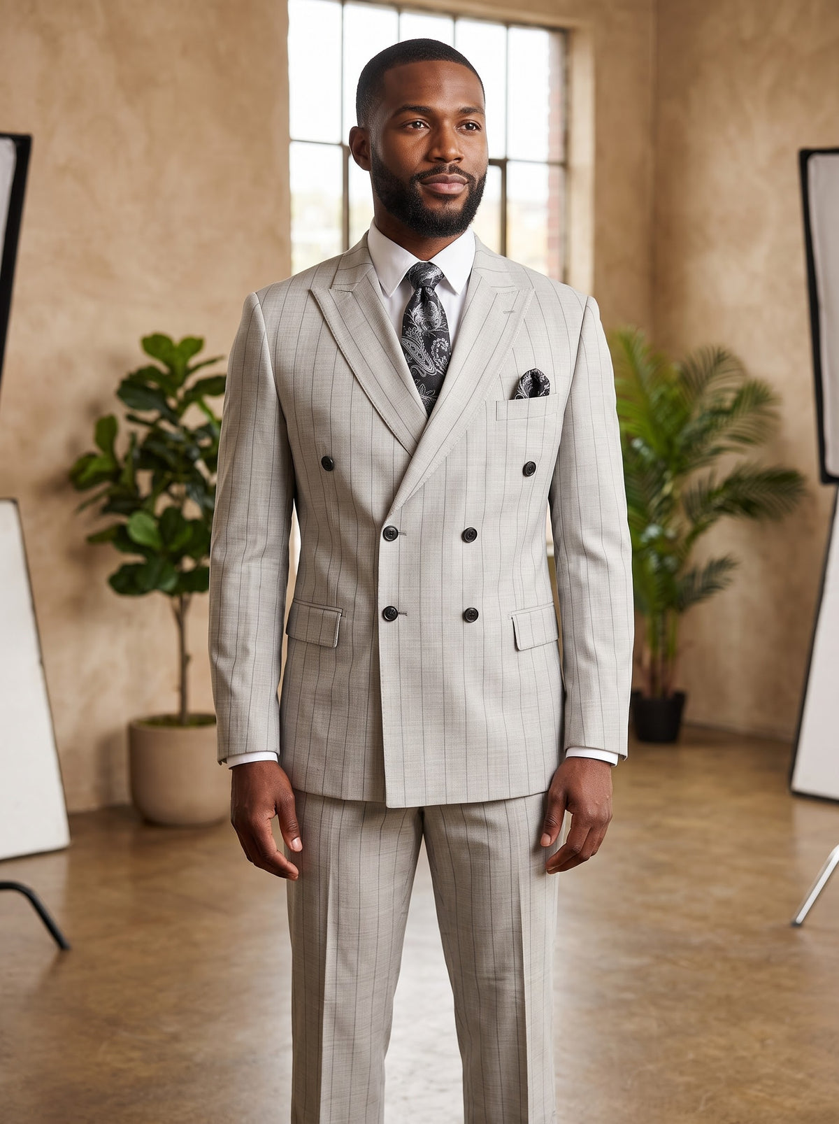 A man wearing a Tiglio Luxe PISTOIA Modern Fit Grey Pinstripe Double Breasted Suit WS8504 in light grey, styled with a white shirt and a dark patterned tie.