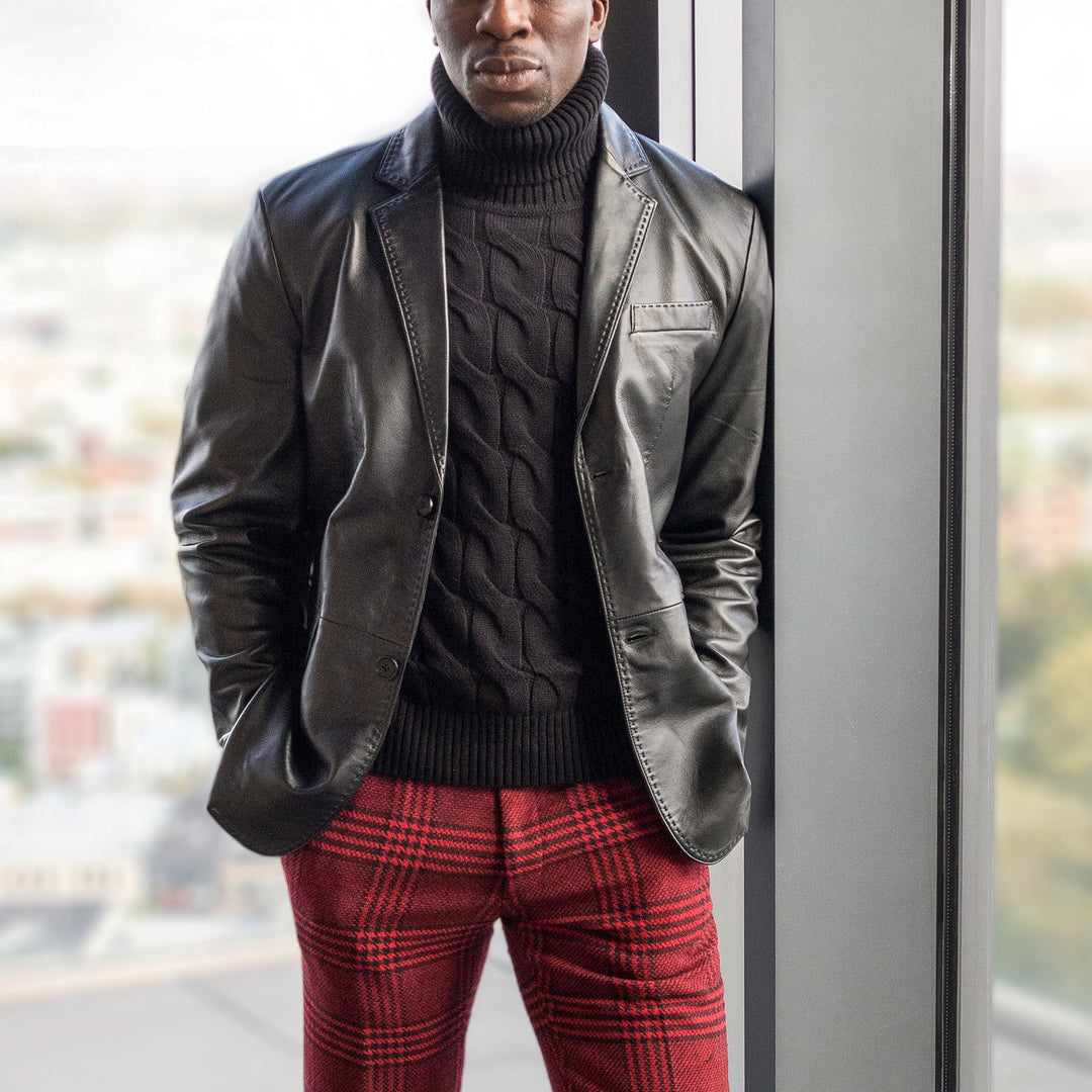 A person stands by a window wearing the Inserch Leather Blazer 600-01 Black by Inserch, paired with a black turtleneck sweater and red plaid pants.