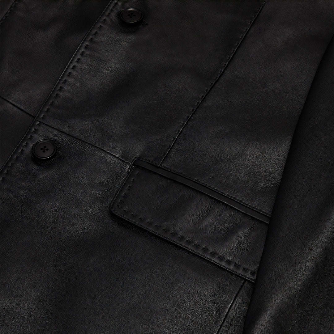 A person stands by a window wearing the Inserch Leather Blazer 600-01 Black by Inserch, paired with a black turtleneck sweater and red plaid pants.