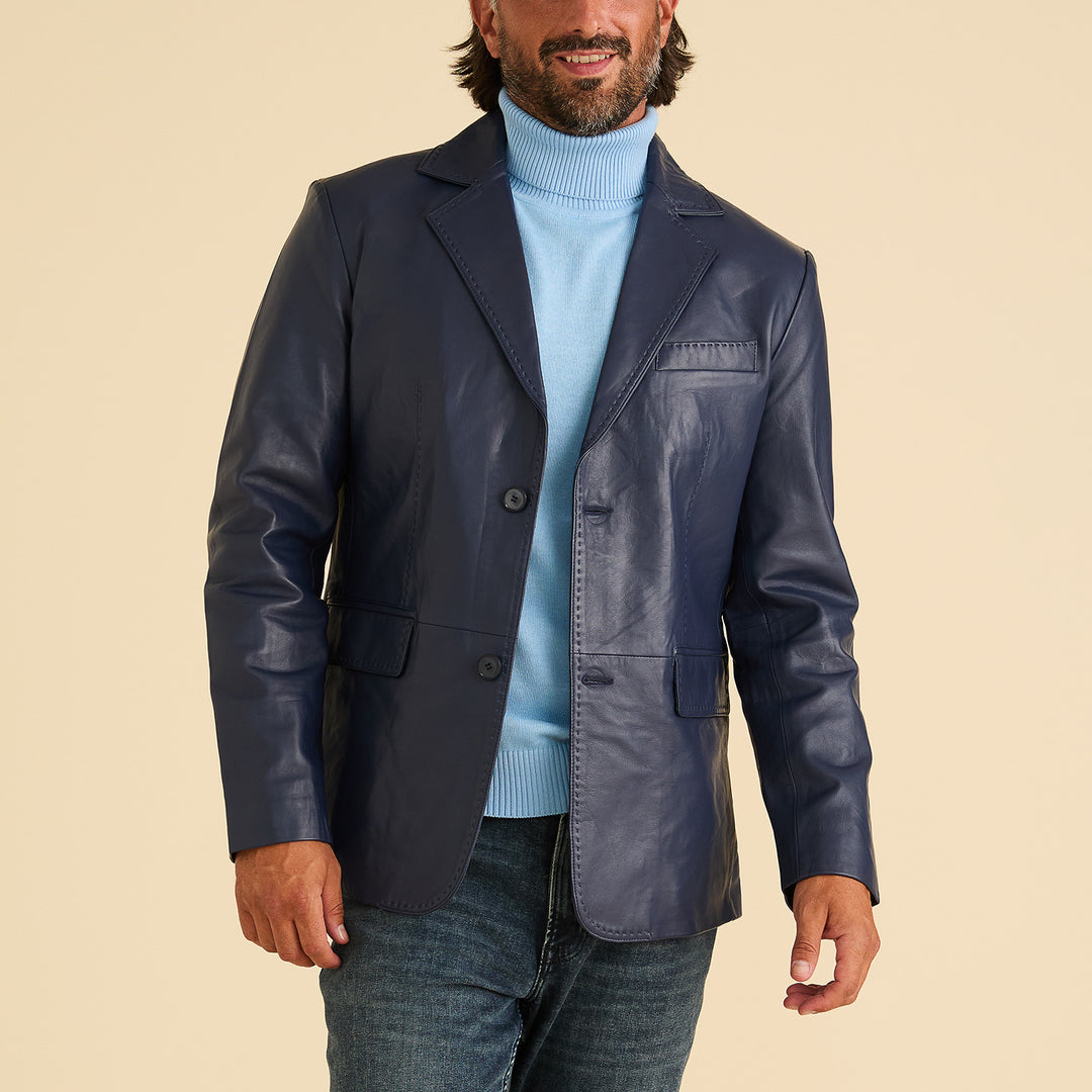 A man wearing the Inserch Leather Blazer 600-11 Navy by Inserch, styled with a light blue turtleneck and blue jeans, poses against a beige background.