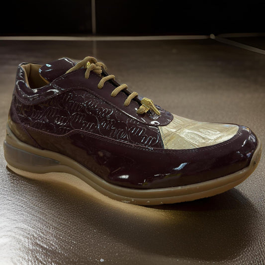 The Mauri 8900 Brown/Tan Patent Leather sneaker, featuring a glossy brown upper, gold accents, and tan laces, rests on a dark reflective surface.