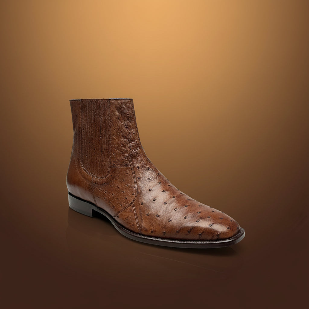 A single Belvedere Shoe 10 in brown ostrich leather (Size 9 only), featuring a square toe, is displayed on a wooden surface with folded clothes in the background. Please note, this BELVEDERE item is clearance and final sale—no exchange or return accepted.