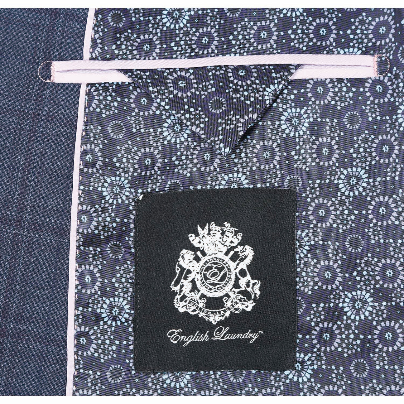 A mannequin is dressed in the English Laundry Gray Wool Suit EL82-66-095, a dark plaid wool suit jacket by English Laundry with a two-button closure, paired with a white dress shirt and a patterned orange tie.