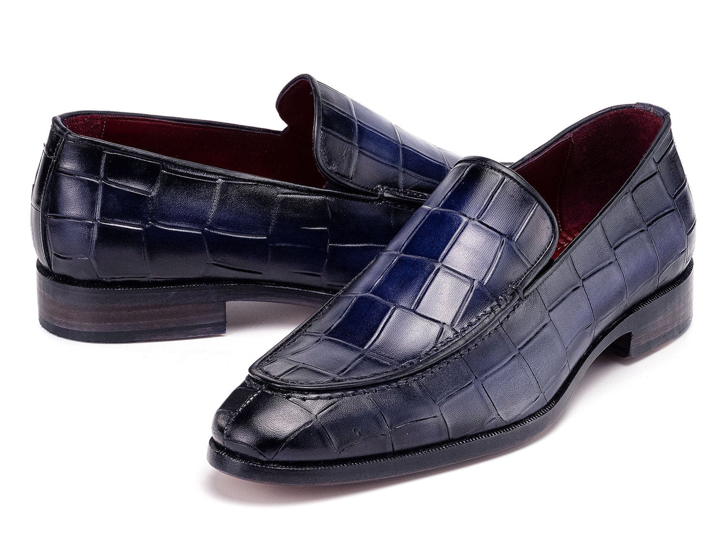 The Paul Parkman Croco Textured Leather Loafer Blue - 7339-BLU, a pair of blue men's loafers with crocodile texture, is shown on a white background—one shoe upright, the other leaning diagonally against it.
