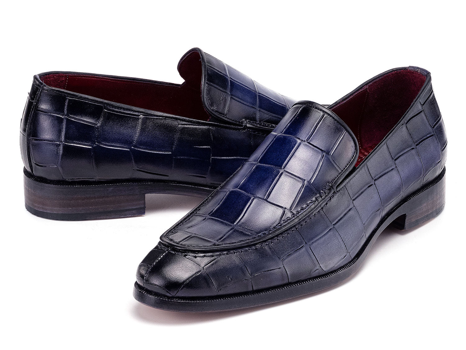 The Paul Parkman Croco Textured Leather Loafer Blue - 7339-BLU, a pair of blue men's loafers with crocodile texture, is shown on a white background—one shoe upright, the other leaning diagonally against it.