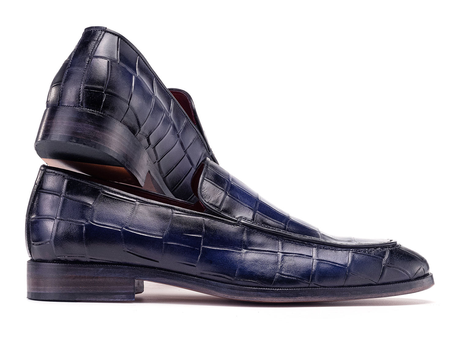 The Paul Parkman Croco Textured Leather Loafer Blue - 7339-BLU, a pair of blue men's loafers with crocodile texture, is shown on a white background—one shoe upright, the other leaning diagonally against it.