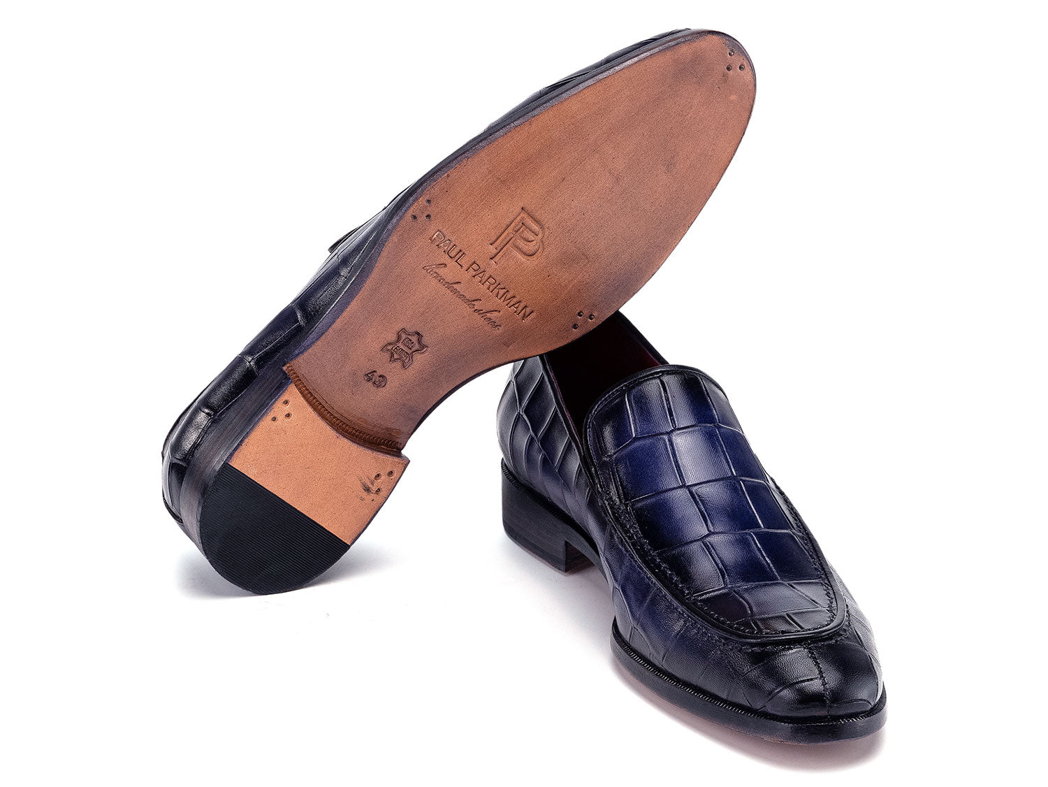 The Paul Parkman Croco Textured Leather Loafer Blue - 7339-BLU, a pair of blue men's loafers with crocodile texture, is shown on a white background—one shoe upright, the other leaning diagonally against it.