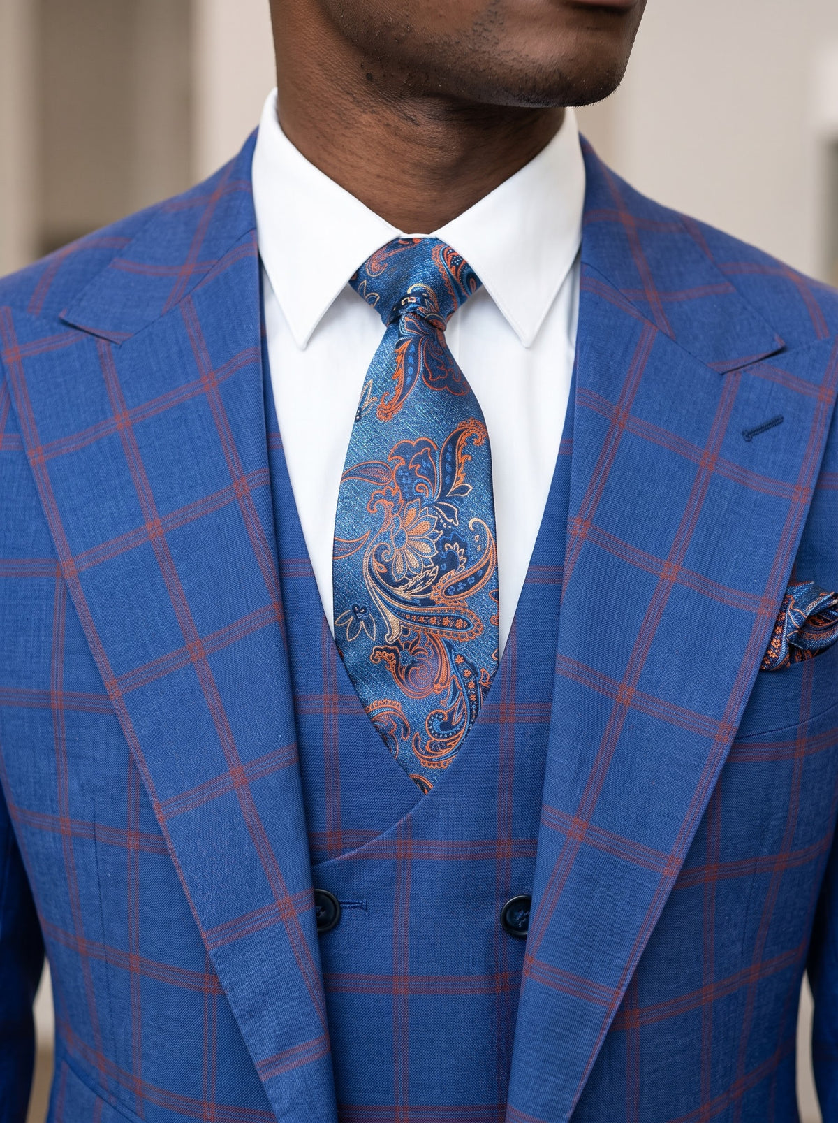 A man wearing a blue and red windowpane Tiglio Rosso Orvietto Semi Wide Leg Blue/Red Windowpane TL8074 three-piece suit, a white dress shirt, and a patterned blue tie.