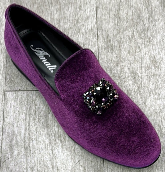 The Exclusive Formal Dress Shoe Purple TIAGO by UNIQUE DESIGN MENSWEAR, featuring a purple velvet design with a black embellished brooch and handcrafted in Italy, sits elegantly on a gray wooden floor.