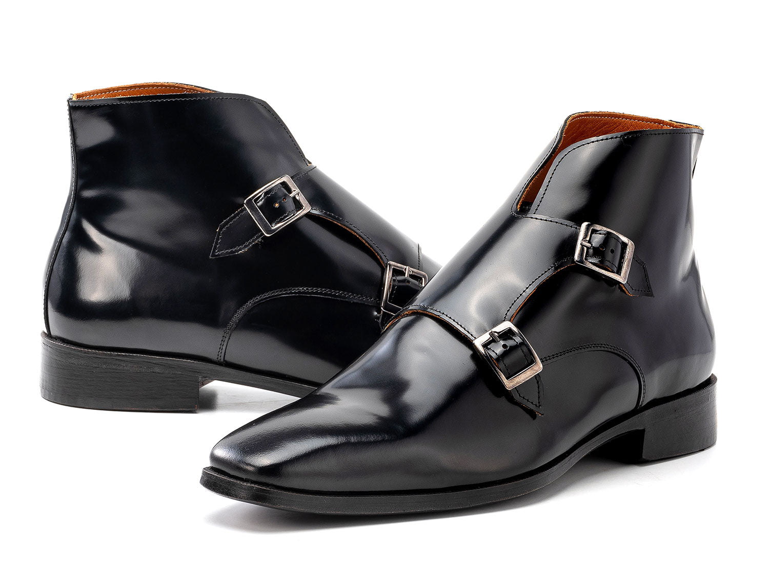 The Paul Parkman Double Monkstrap Ankle Boots in black polished leather (model 8154-BLP) feature side buckles; one men's boot stands upright while the other is balanced on top.