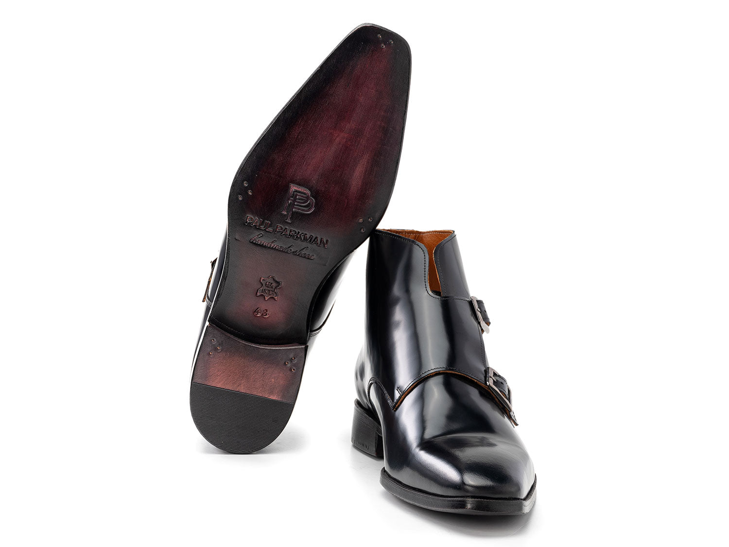 The Paul Parkman Double Monkstrap Ankle Boots in black polished leather (model 8154-BLP) feature side buckles; one men's boot stands upright while the other is balanced on top.