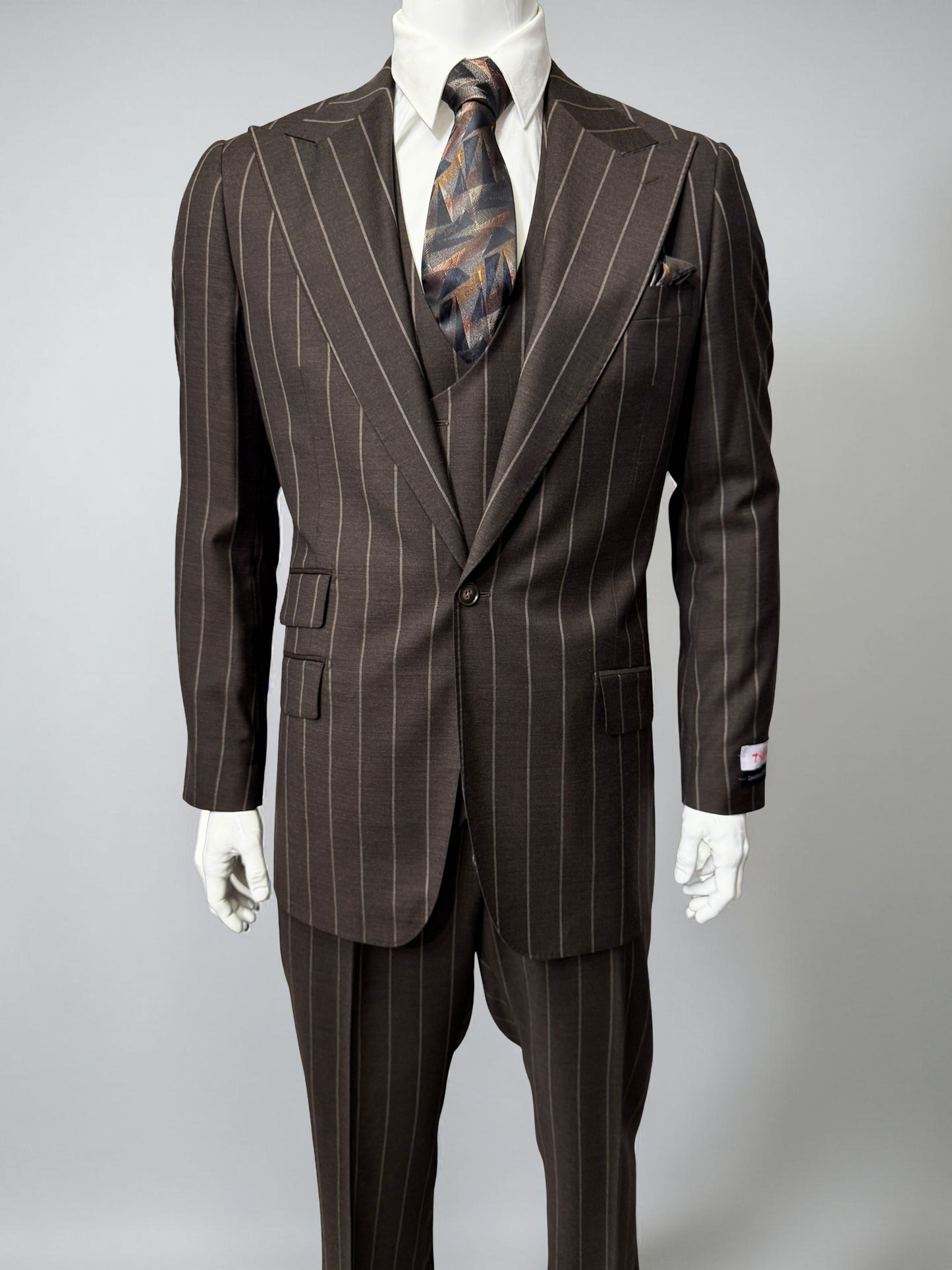 A mannequin displays the Tiglio Rosso Orvietto Brown Pinstripe TL8101 suit with a white shirt and patterned tie, highlighting the classic style of Tiglio Rosso against a simple light background.
