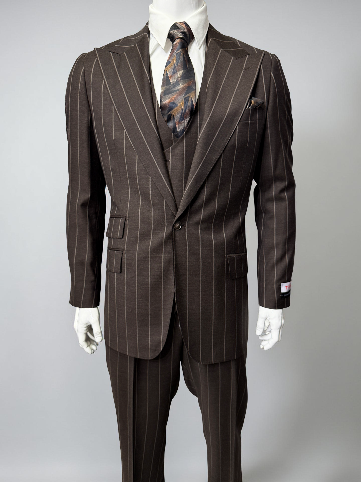 A mannequin displays the Tiglio Rosso Orvietto Brown Pinstripe TL8101 suit with a white shirt and patterned tie, highlighting the classic style of Tiglio Rosso against a simple light background.