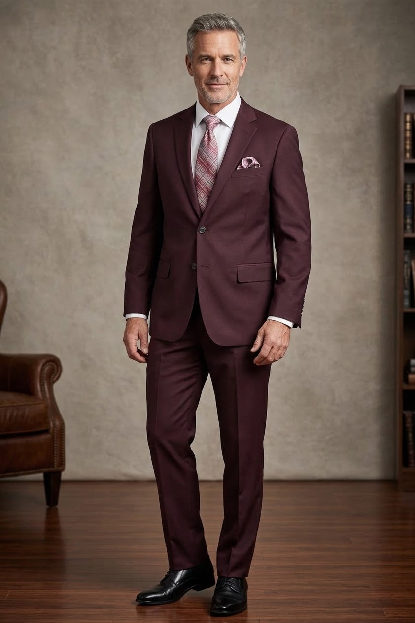 The Tiglio Luxe Novello Burgundy Suit showcases a refined European fit, complete with a geometric patterned tie and matching pocket square on a sleek white shirt, all meticulously crafted from exquisite Italian wool by Tiglio.