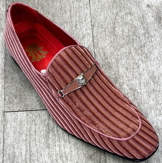 The Exclusive Formal Dress Shoe Pink 6946 by UNIQUE DESIGN MENSWEAR, a pink suede leather loafer with a metal emblem on the strap and a red interior, is placed on a gray wooden surface.