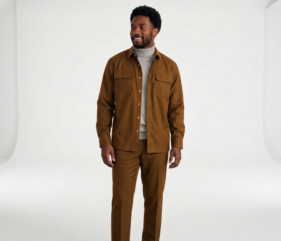 A man wearing the Inserch Two-Pocket 2pc Set SE004-00027 Aztec by Inserch—a regular fit, long sleeve brown button-up shirt with front pockets and matching pants—over a light gray turtleneck, standing and smiling.