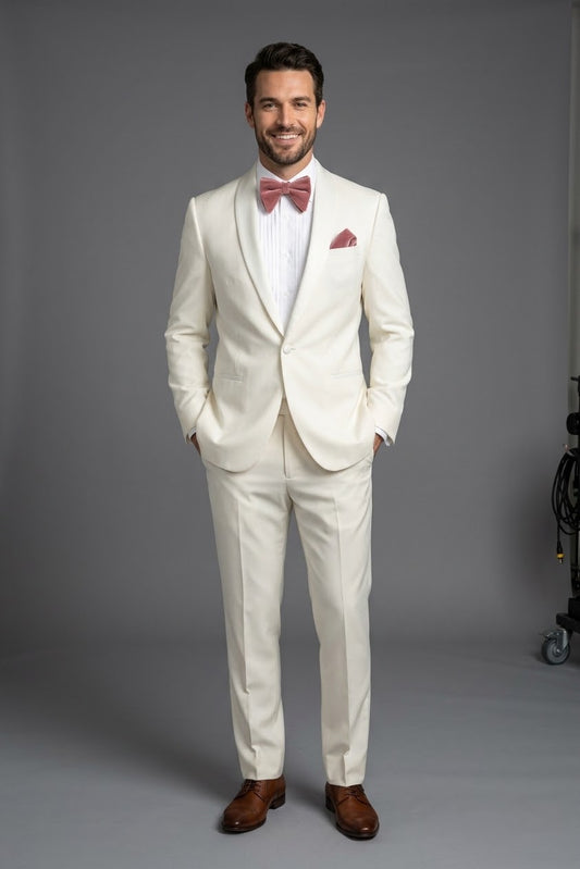The Tiglio Luxe Beckham Modern Fit Off White Pure Wool Tuxedo from Tiglio Luxe, featuring satin lapels and crafted from luxury Italian fabric, is paired with a white dress shirt, a pink velvet bow tie, and a matching pink pocket square—all presented on a headless mannequin.